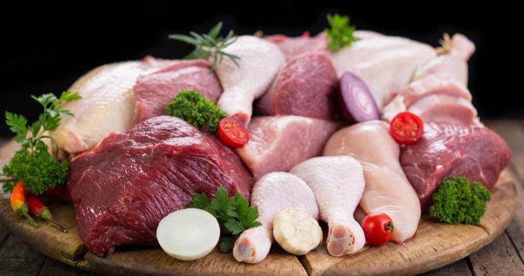 Różnego rodzaju mięsa leżą na drewnianej desce. 