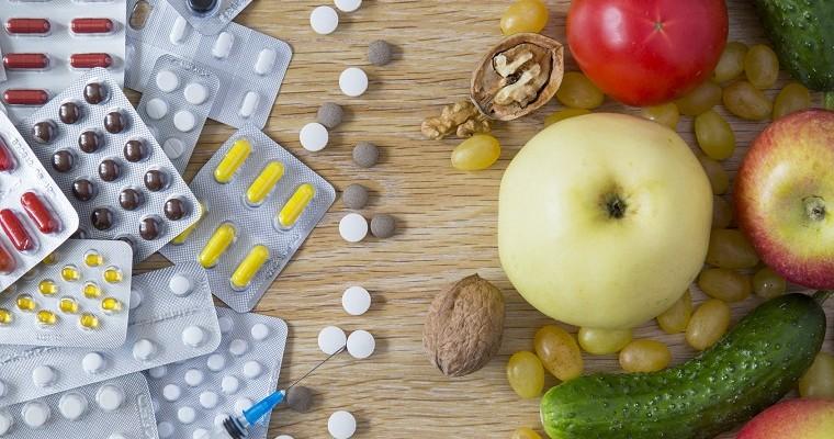 Suplementy i tabletki obok owoce i warzywa