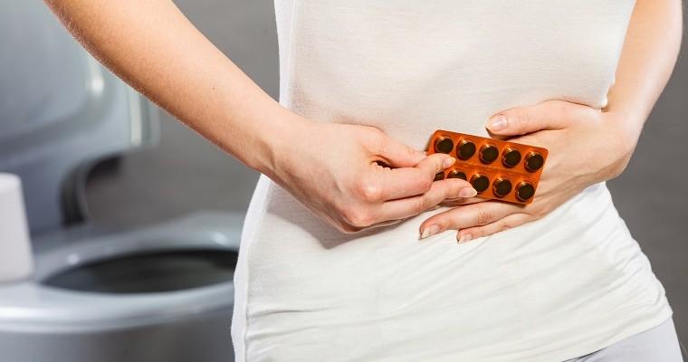 Kobieta trzyma tabletki na ból brzucha