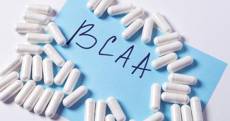 Aminokwasy BCAA - tabletki leżą na niebieskim tle.