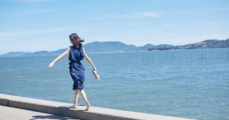 Młoda kobieta spaceruje brzegiem morza. Hygge