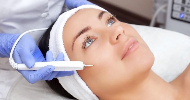 Kobieta u kosmetyczki poddaje się zabiegowi laserowego usuwania blizn. Zbliżenie na twarz