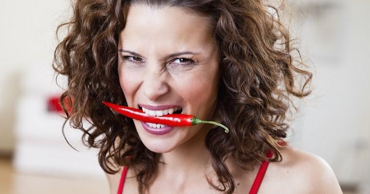 Kobieta z papryczką chili w ustach. 