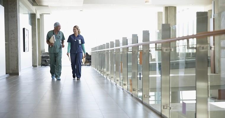Lekarz i pielęgniarka spacerują korytarzem szpitala. 