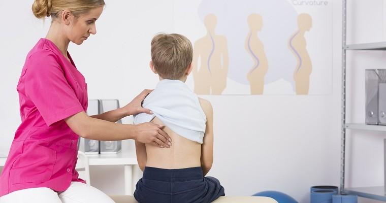 Ortopeda bada kręgosłup chłopca. 