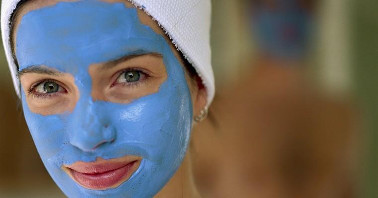 Kobieta z nałożoną maseczką z niebieskiej glinki na twarz. 
