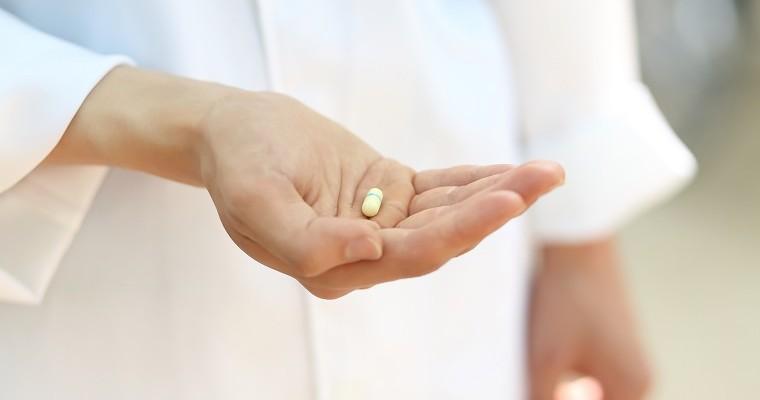 Farmaceuta trzyma tabletki na dłoni.
