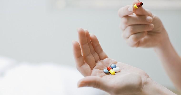 kobieta trzyma dłoni kolorowe tabletki 