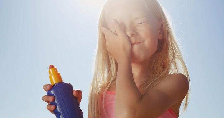 Mała dziewczynka stosuje krem ​​przeciwsłoneczny na twarz