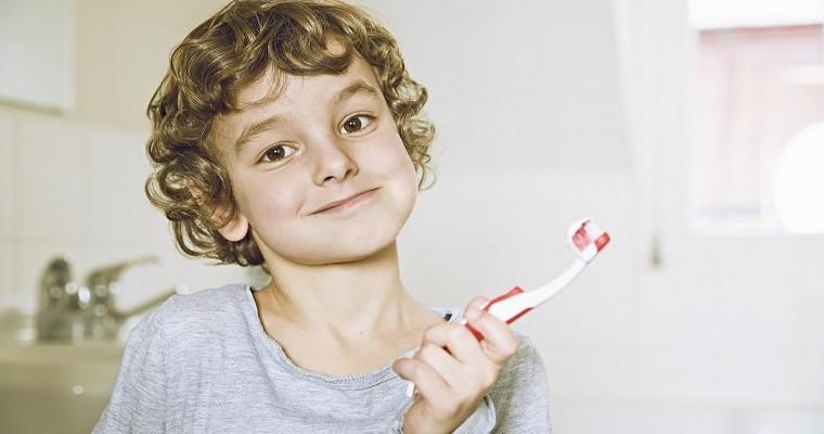 Uśmiechnięty chłopiec w łazience trzymając szczoteczkę do zębów