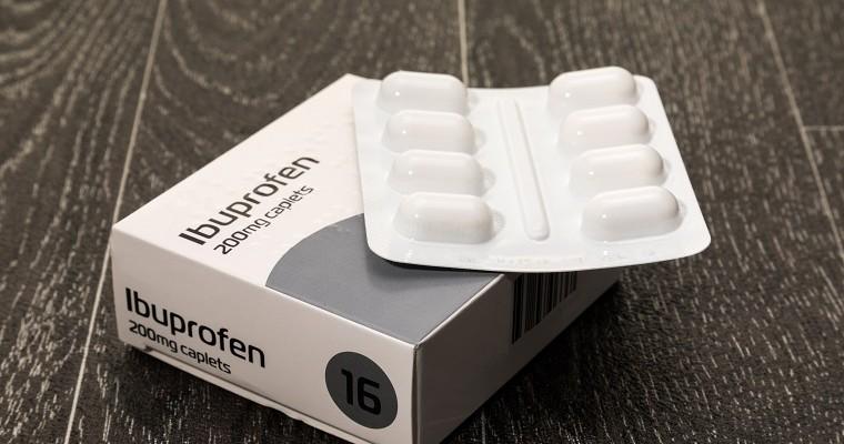 Ibuprofen tabletki leżą na drewnianym blacie. 