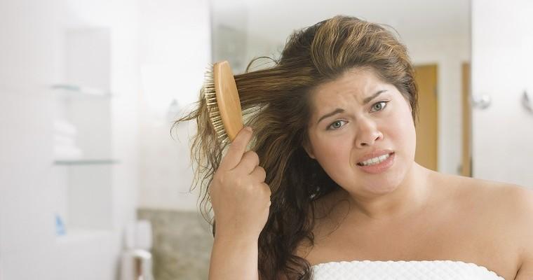 młoda kobieta ma problem z rozczesaniem włosów 