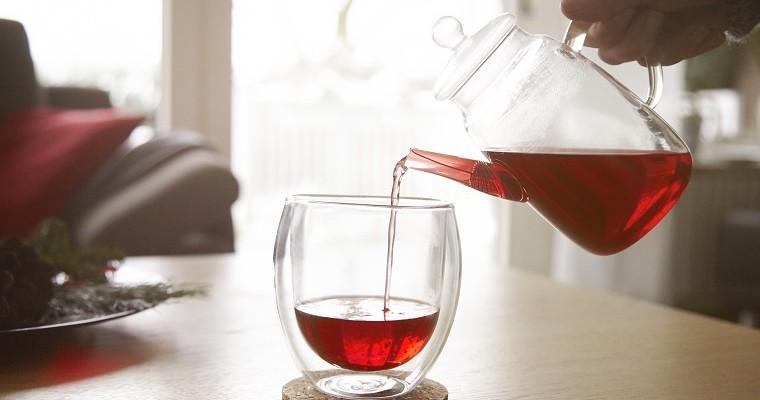  Kobieta nalewa czerwoną herbatę do szklanki.