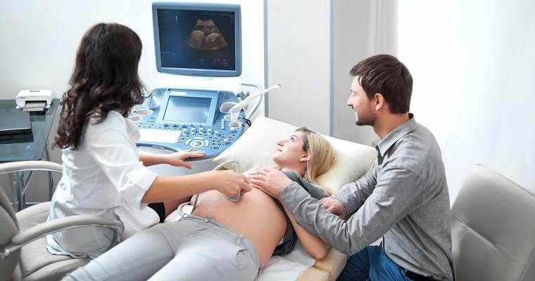 Kobieta w ciąży w czasie badania USG. Przyszli rodzice w gabinecie lekarskim na badaniu USG