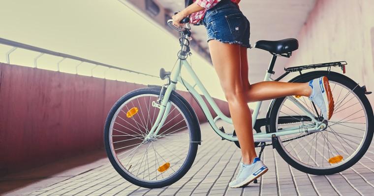Nogi kobiety stojącej obok roweru